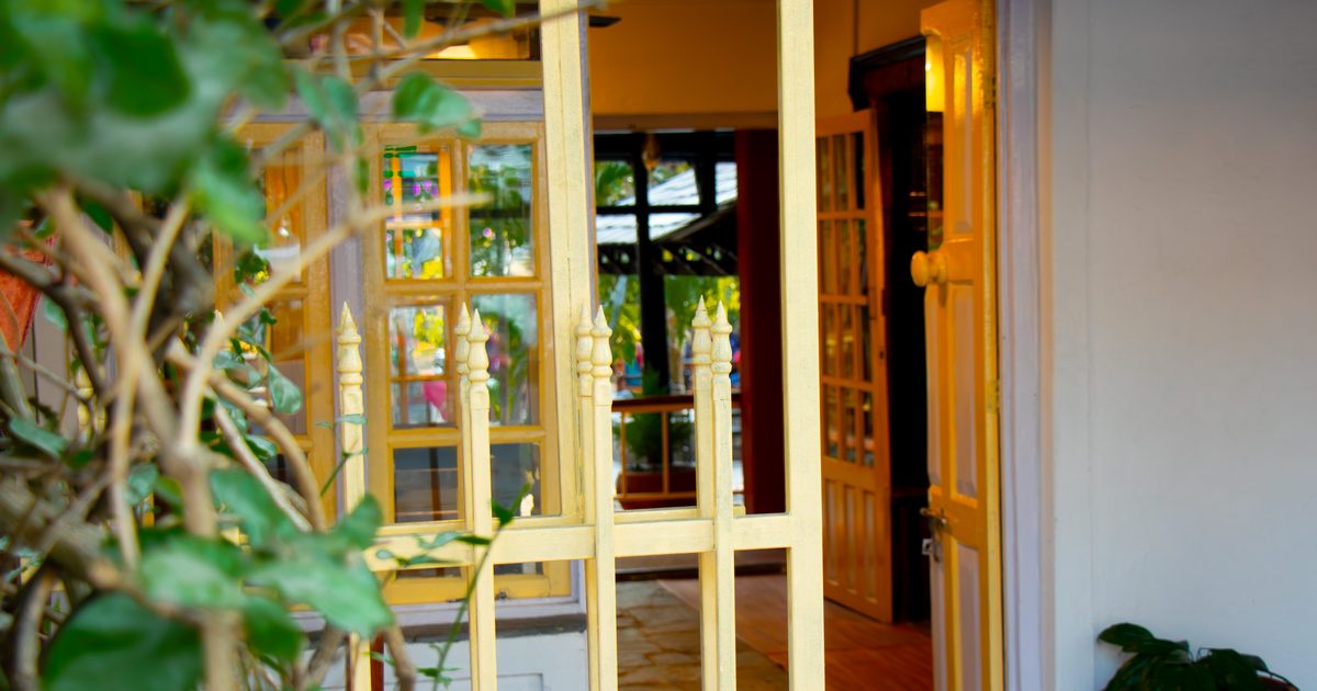 Open yellow gate and door leading into a warm, light-filled interior