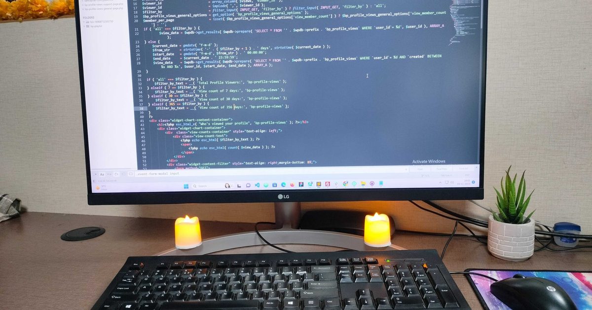 Developer desk with a monitor displaying code, keyboard and candles